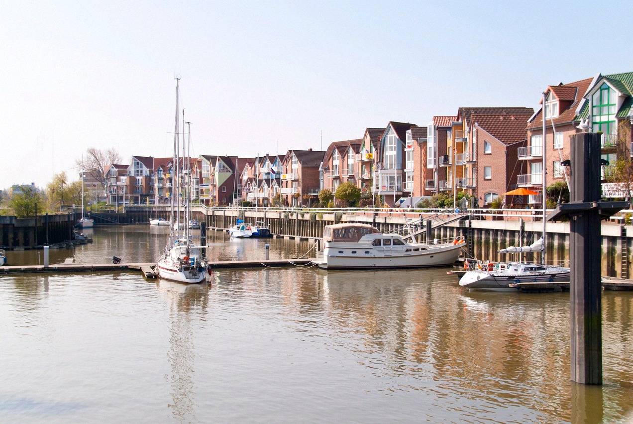 A quiet boat harbour in Cuxhaven with moored sailing and motor boats in front of red