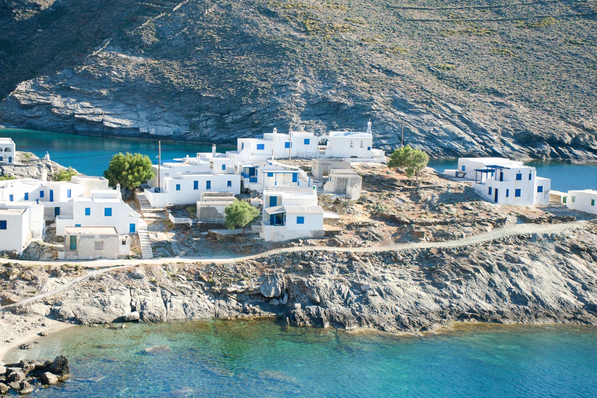 Small coastal hamlet on Folegandros with whitewashed houses right on the rocky