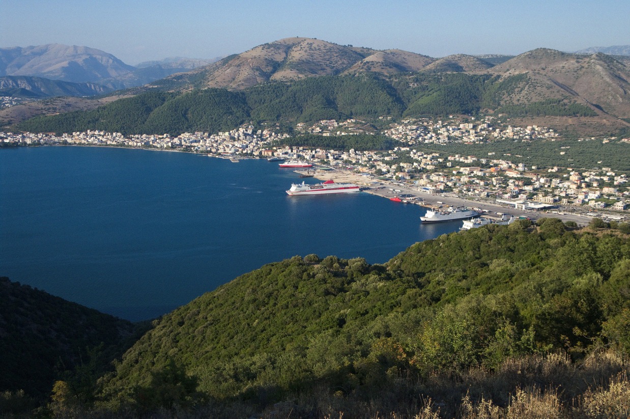 Blick von den bewaldeten Hügeln auf den Fährhafen von Igoumenitsa mit Fähren an den Liegeplätzen und der Stadt entlang der Bucht