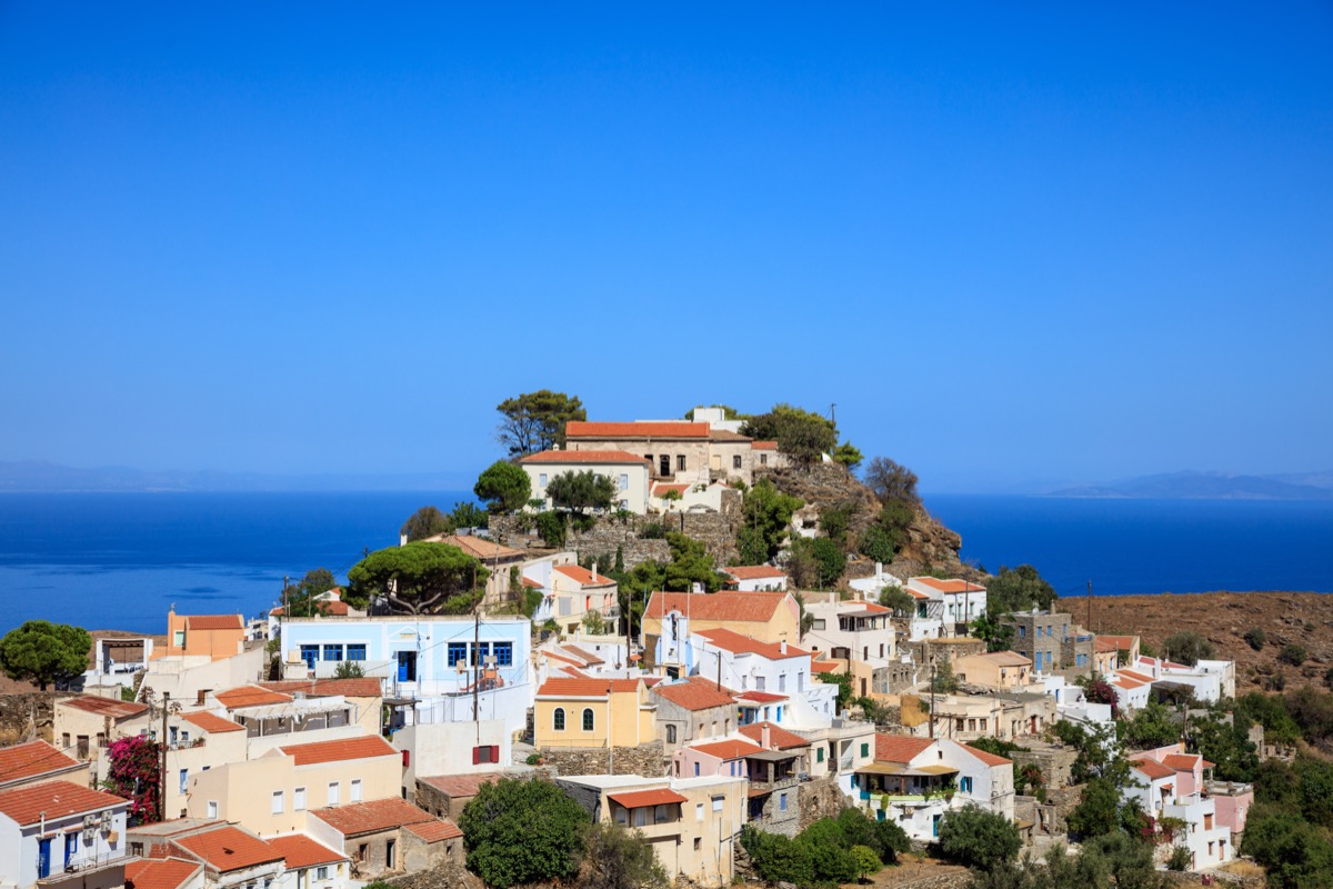 Picturesque hillside village on the island of Ikaria with colorful houses and pines on the summit