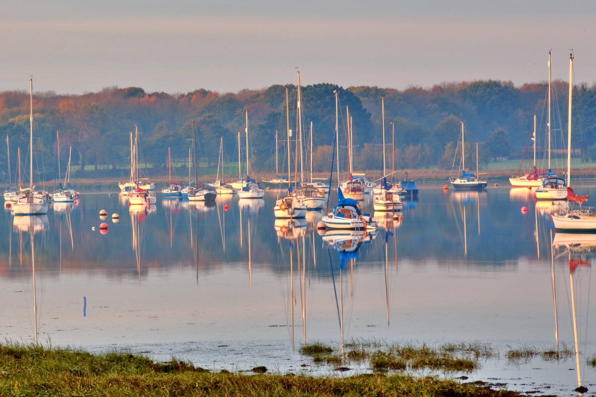 Sailboats resting in the morning autumn mist in Chichester Harbour near Fishbourne