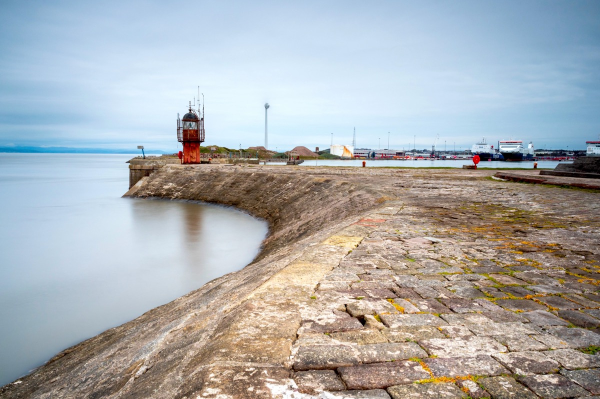 Long-exposure shot of the old red lighthouse at the end of Heysham pier with the calm harbor basin
