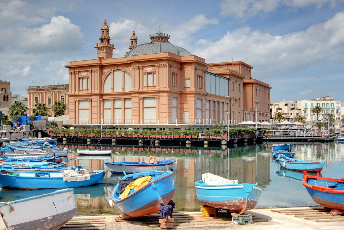 Blue fishing boats in Bari harbour in front of the historic Teatro Margherita