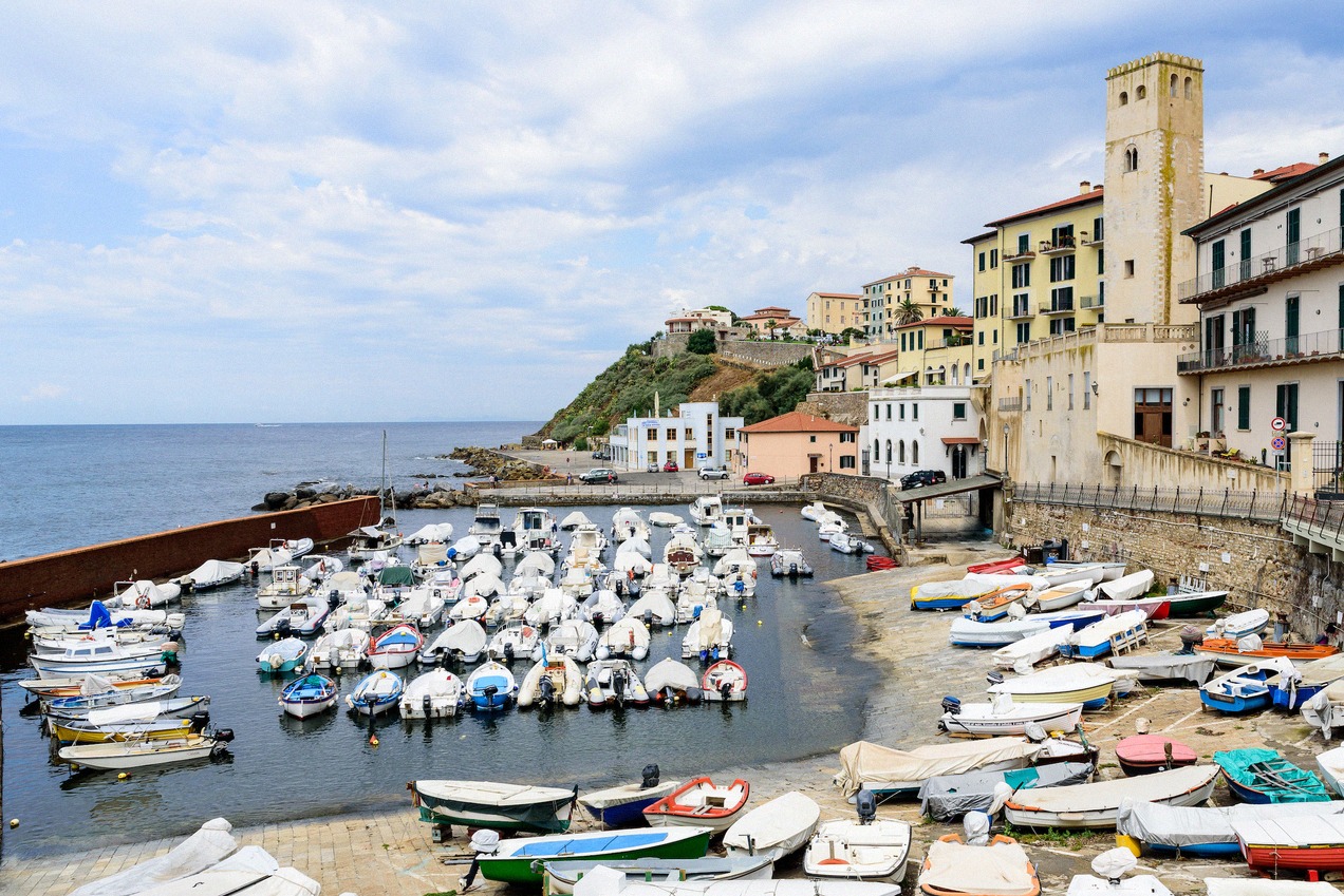 Small fishing harbour of Piombino with closely moored boats and the picturesque old town