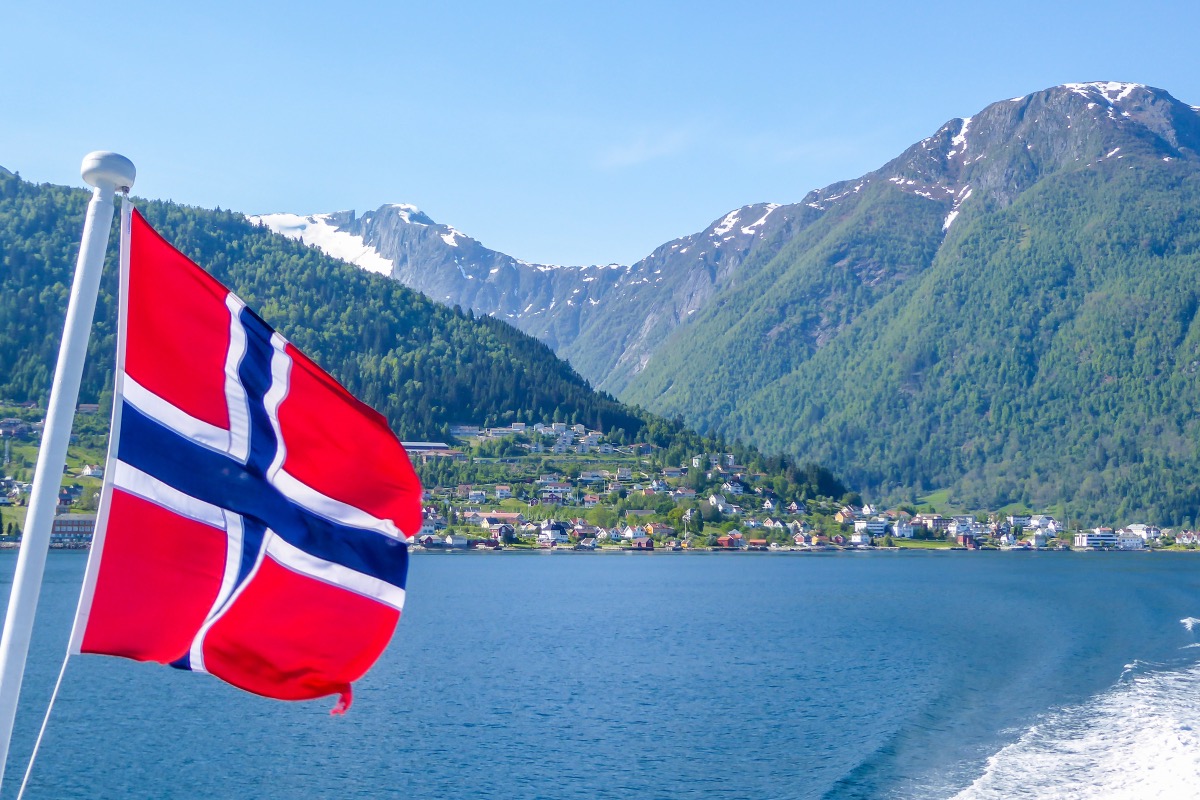 Norwegian flag flying from the stern of a ferry over choppy fjord waters