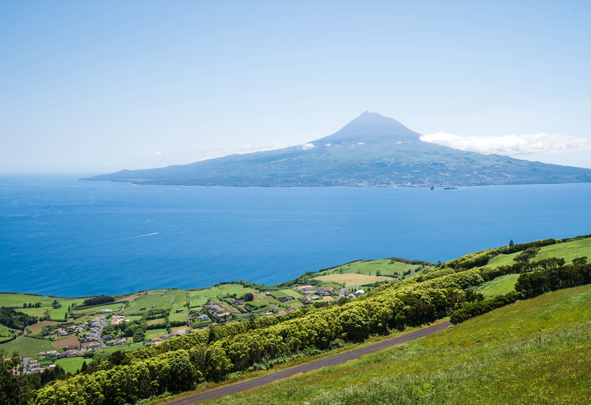 View from the green coast of Faial island across the Atlantic to the towering Pico volcano