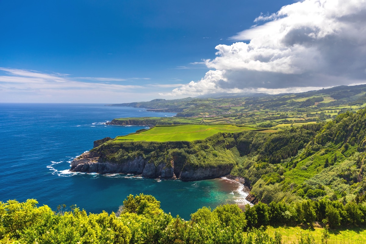 Gruene Kueste der Azoreninsel Sao Miguel mit steilen Klippen, sattgruenen Feldern und tiefblauem Atlantik