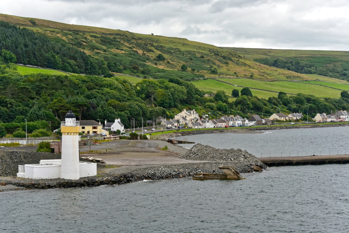 Lighthouse on the shore of Cairnryan on Loch Ryan with the village behind