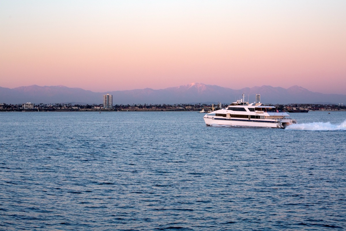 A white ferry crosses the calm bay of Long Beach, California, at sunset